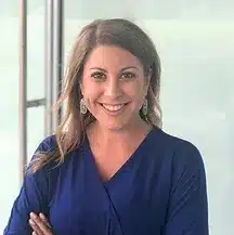 A headshot of Ashley French, a middle aged woman wearing a blue shirt.