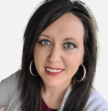 A headshot of Dawn Smith, a middle-aged woman with brown hair, wearing hoop earrings and a gray sweater.