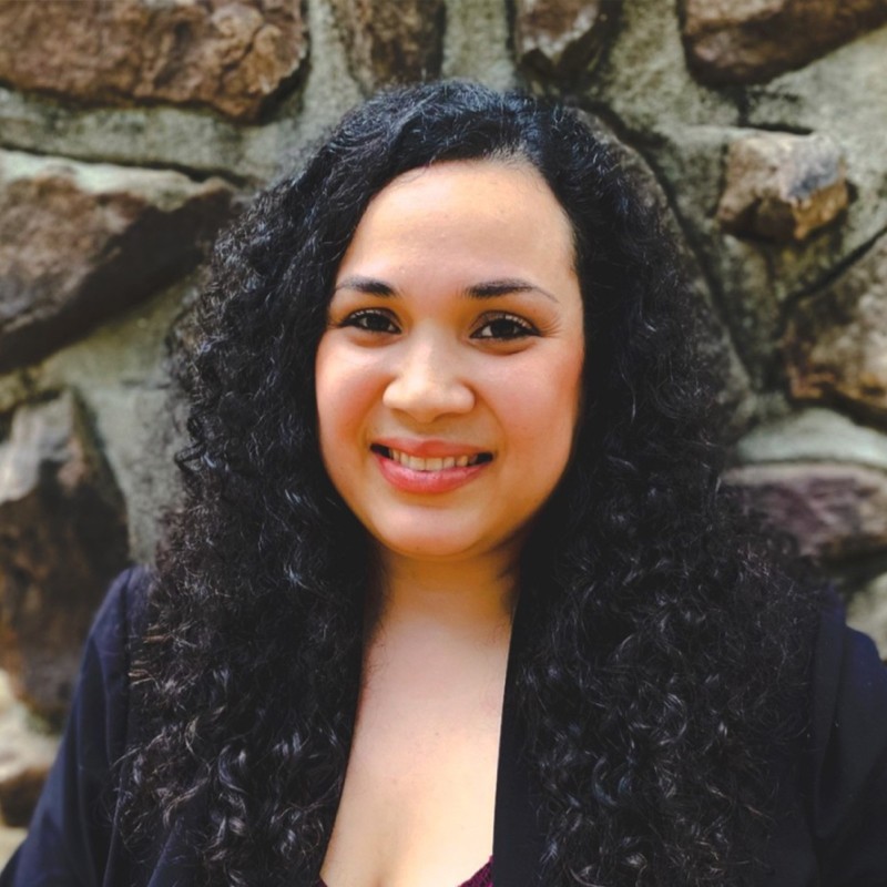 A headshot of Deloris Penn, a woman with curly, long black hair.
