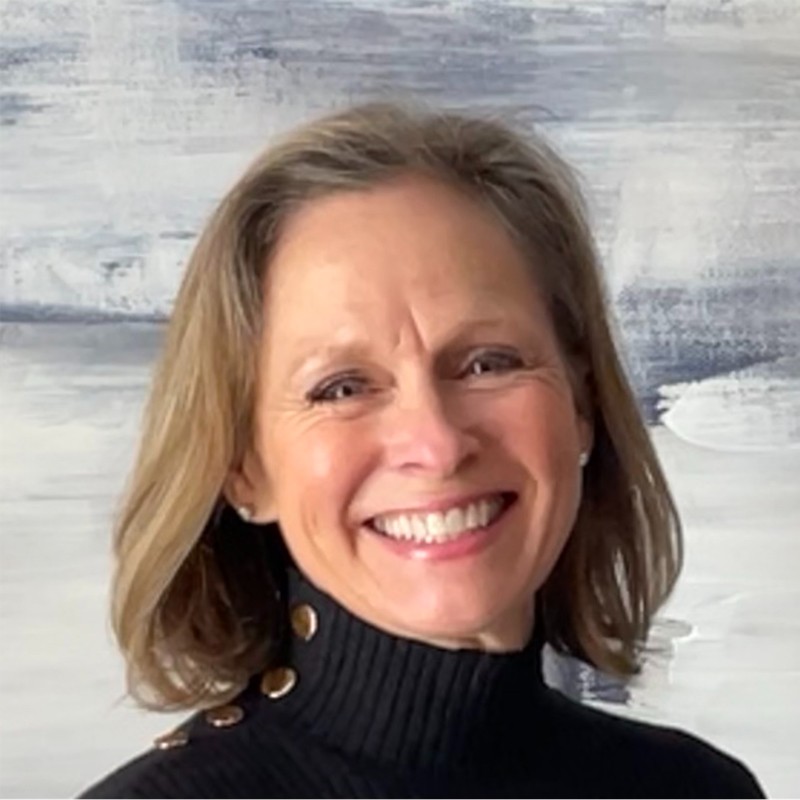 A headshot of an older woman with short brown hair wearing a black turtleneck sweater.