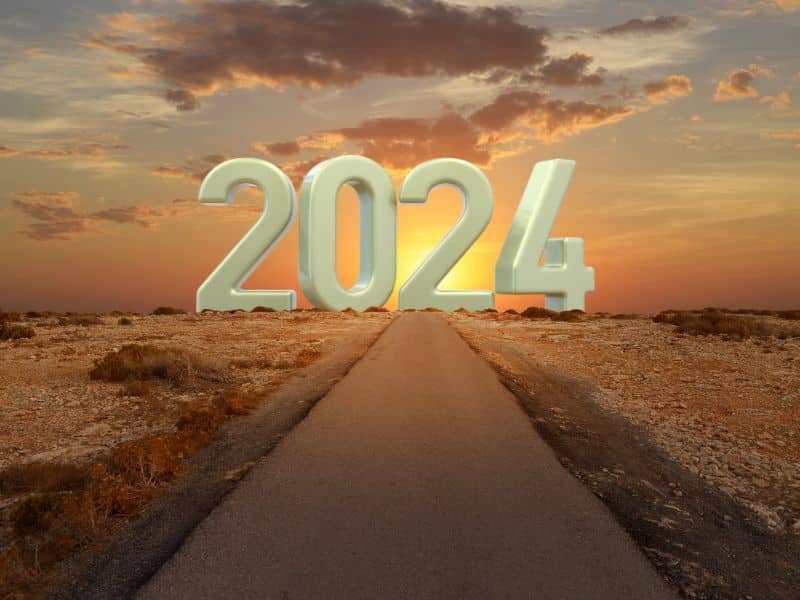 A desert road landscape with a giant white 2024 sitting against the sky.