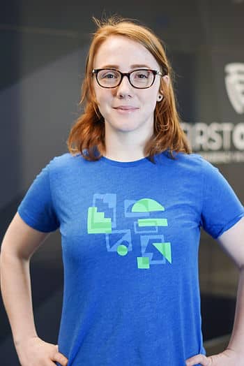 A red-haired woman posing for the camera wearing a blue t-shirt.