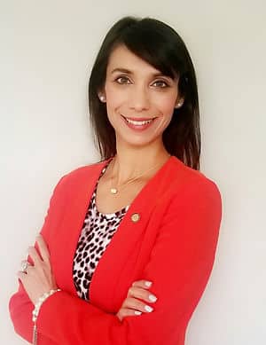 A headshot of a woman with black hair wearing a cheetah print shirt with a bright red sweater.